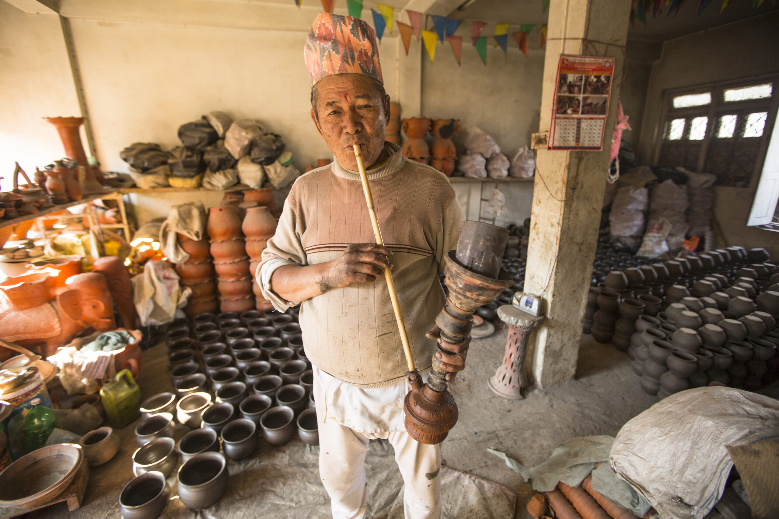 Bhaktapur, Nepal- December 7, 2013: Unidentified Nepalese man smokes  in the his pottery workshop. More 100 cultural groups have created an image Bhaktapur as Capital of Nepal Arts.