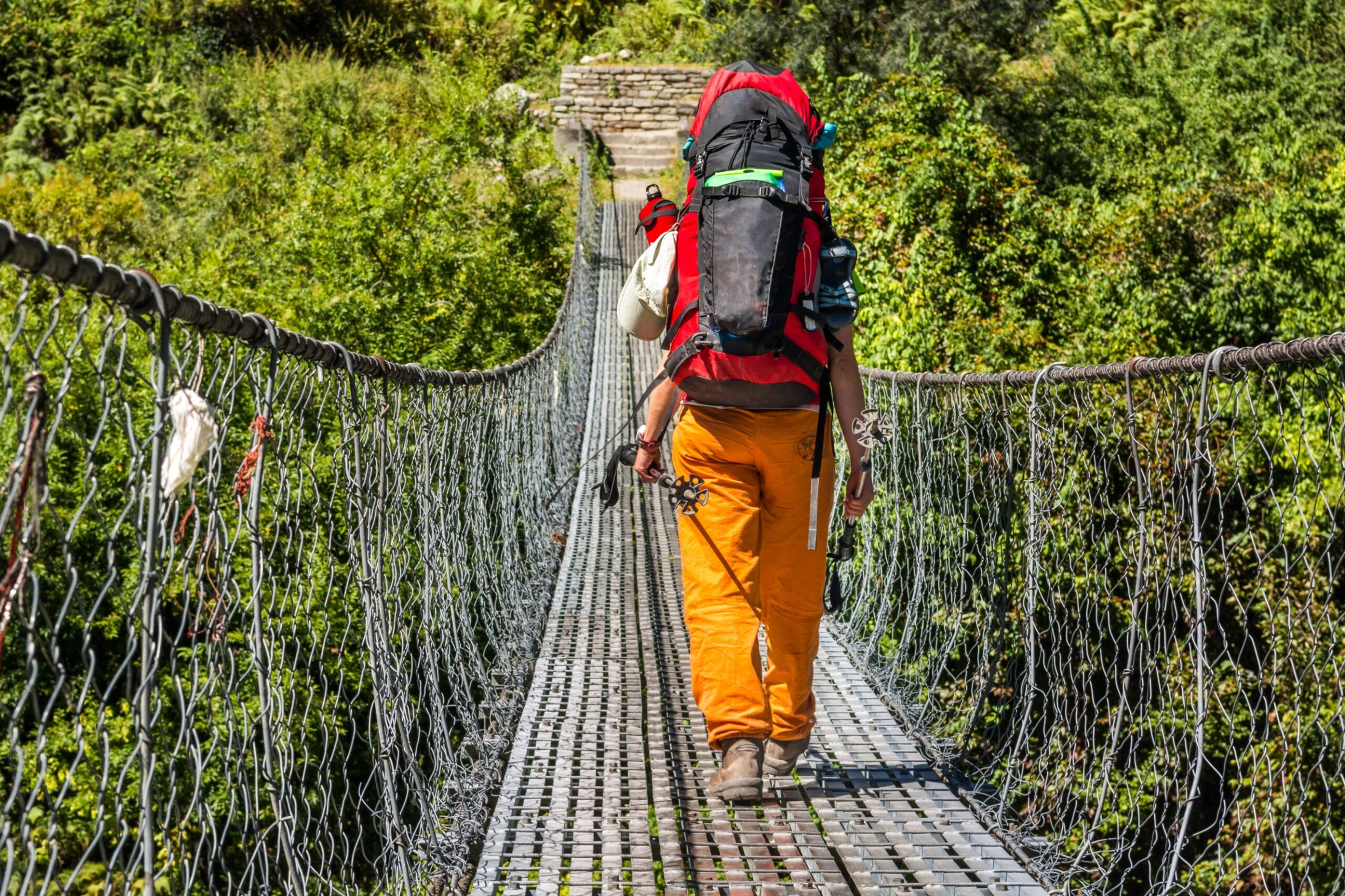 Female hiker crossing a suspension bridge. Treking Annapurna circuit.